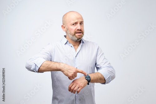 Mature european businessman impatiently pointing to his watch. Why are you late concept.