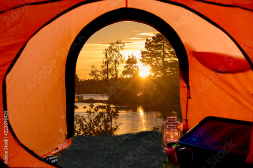 view out of a tent, lake in the background, sunset