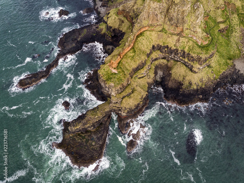 Causeway Coast near Giant's Causeway without tourists aerial view of waves and basalt rocks.