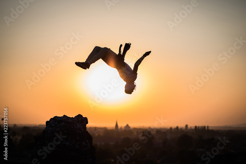 boy doing somersault on sunset background