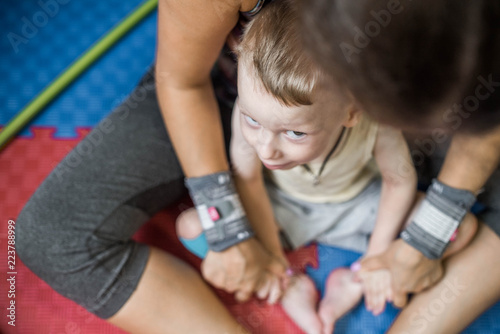 Physical therapist stretching little boy with cerebral palsy