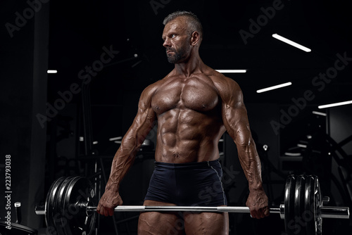 Brutal adult athlete posing in the gym.