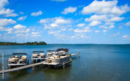 Boat dock with raised pontoons on beautiful lake in northern Minnesota with blue sky and fluffy clouds