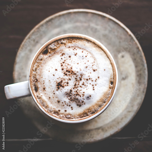 Top view of a cup of cappuccino or latte coffee with a foam white on a wooden background in a cafe.