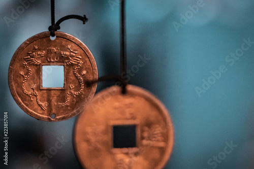 Oriental, magical pendants. Traditional asiatic and chinese currency, transformed into fortune coins with powerful engravings. Bronze, copper, gold necklace, black thread, blurry background. 