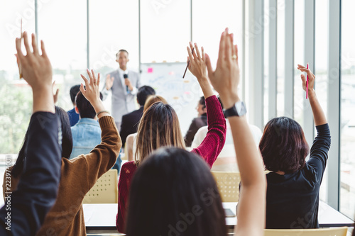 Group of business people raise hands up to agree with speaker in the meeting room seminar