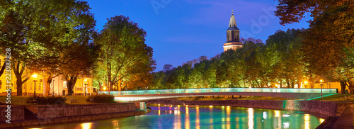  The night panoramic view of Aura river in Turku, Finland with a clock tower of cathedral and bridge on a background. 