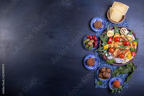 Set collection of cheese and snacks. Halloumi, belper knolle, olives, tzatziki sauce over on deep blue black background. Overhead. Copy Space.