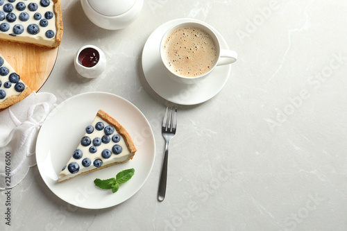 Flat lay composition with piece of tasty blueberry cake and space for text on gray table