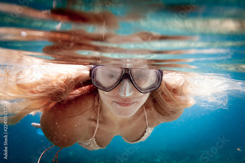 Beautiful woman with long hair underwater snorkeling in the tropical water