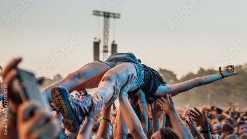 Crowd surfing - audience carry the young woman on their hands during rock concert.