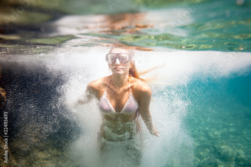 Young woman jumping to water, underwater image