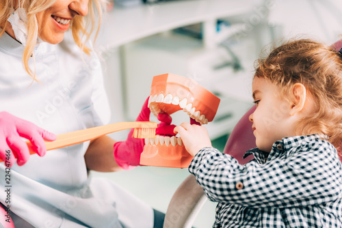 Little girl at dental clinic, learning how to brush teeth correctly