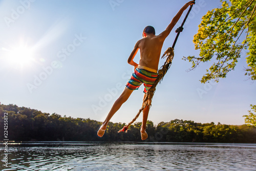 bungee jumping. the boy in free fall over the water. Back view. Copy space for your text