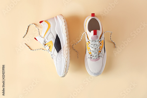 Pair of stylish sneakers on color background, top view