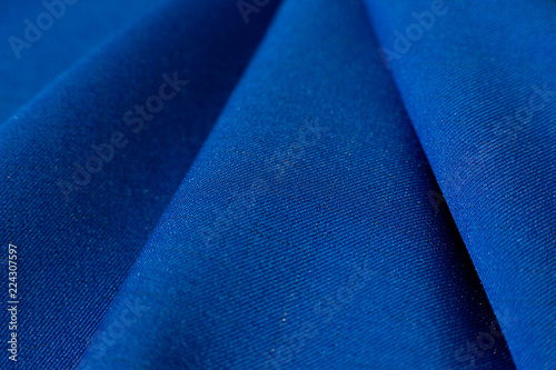 Texture of fabric and folds. A blue gabardine fabric creates a background. Fabric for sewing fashionable and stylish clothes.