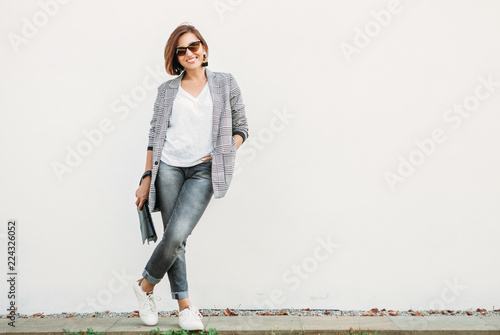 Uśmiechnięta kobieta pozuje w przypadkowym miasto stroju w czerni i siwieje kolory