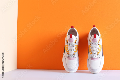 Pair of stylish sneakers near color wall, space for text