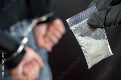 Police arrest drug trafficker with handcuffs. police officer finds A Little Bag Of Drugs during the search of drug dealer