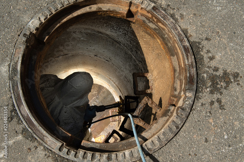 Abwassersysteme, Reparatur an in der Straße eingelssenen Kanalschacht, entfernen von Steigeisen