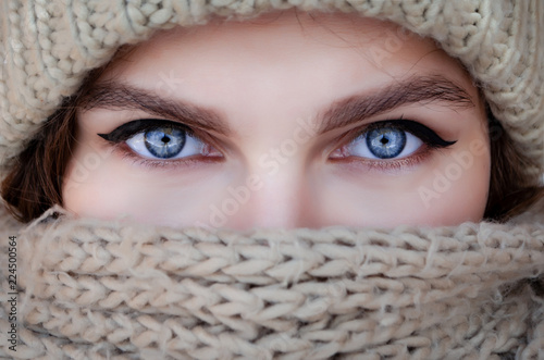 Close-up portrait of a woman in a scarf and hat with beautiful blue eyes
