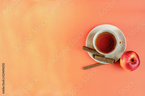 warm color background with hot cinnamon and aplle flavour tea in a white porcelain cup