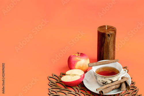 Autumn afternoon hot tea, apple and cinnamon flavour, orange background
