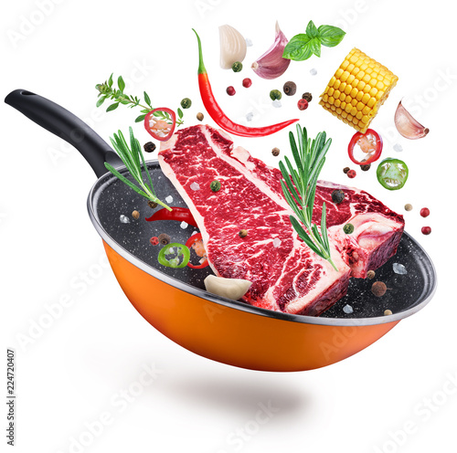 Flying T-bone steak and spices over a frying pan. File contains clipping path.