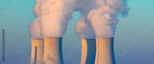 cooling towers with water steam in morning light, nuclear plant