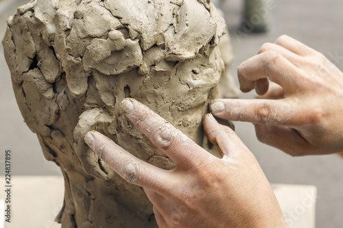 sculptor creates a bust and puts his hands clay on the skeleton of the sculpture. Close-up