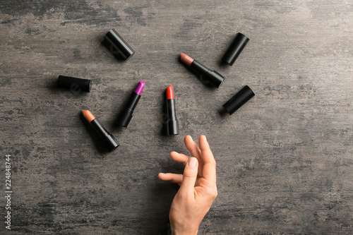 Female hand and colorful lipsticks on dark wooden table