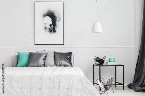 Minimalist, framed poster mock-up on a white wall of an artistic bedroom interior with elegant decor and gray textiles