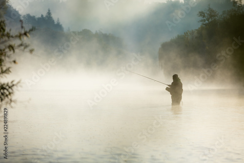 Fisherman holding fishing rod, standing in river