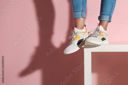 Kobieta w eleganckich sneakers blisko kolor ściany, zbliżenie. Miejsce na tekst
