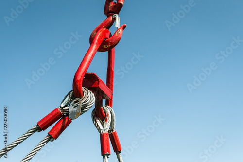 hook of a crane lifts a load on the background of blue sky