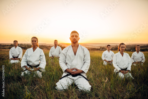 Grupa karate siedzi na ziemi i medytuje