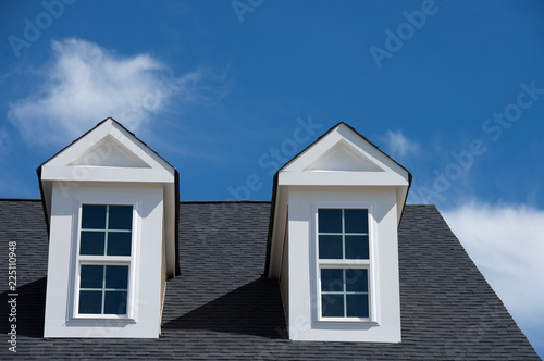 typical American house with dormer window with a gable roof blue cloudy sky background on a new construction in Maryland