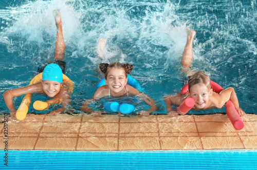 Małe dzieci z makaronem pływackim w krytym basenie