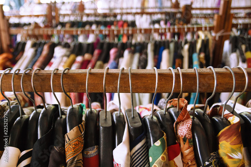 Wooden clothes racks with hangers and with colorful clothes inside a shop.