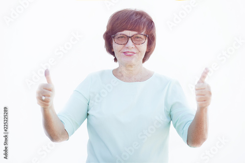 Happy old Asian lady holding thumbs up on the white background. Elderly woman giving a thumb up and looking at the camera