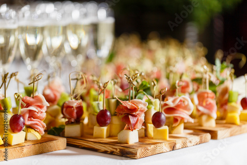 the buffet at the reception. Glasses of wine and champagne. Assortment of canapes on wooden board. Banquet service. catering food, snacks with cheese, jamon, prosciutto and fruit