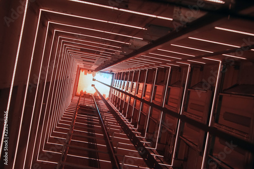 Elevator corridor in the building lit by red elumination. Futuristic elevator shaft is located in a high tower. Lift shaft in a residential building. Abstract, background. Bottom view.