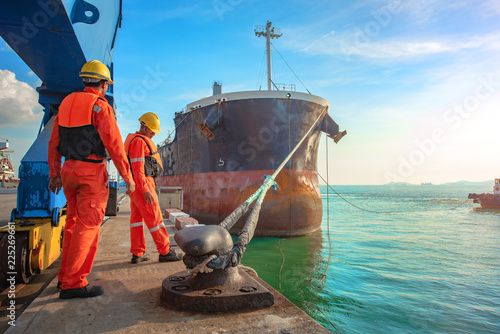 ship vessel is on leaving departure from the port terminal after completion of loading/discharging operation by gang of mooring attending at last party, tug boat standing by to safety assist towage