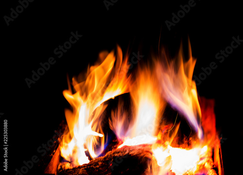 Bright burning firewood in the brazier, hot flame on a dark background, fire, sparks.