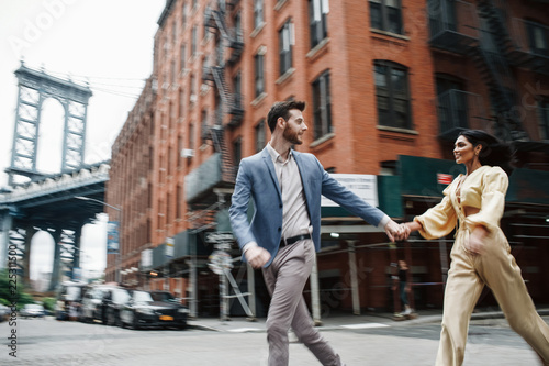 Love story in New York. Indian woman in bright yellow clothes and handsome American man hold each other hands walking around the New York