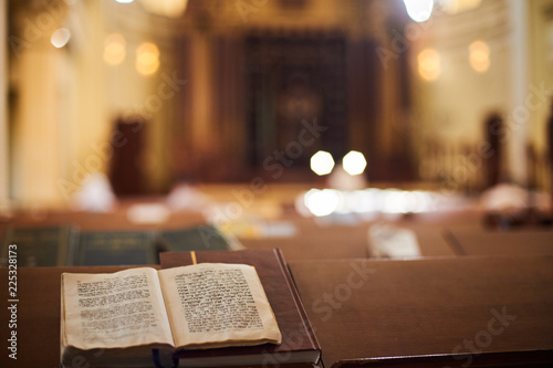 Inside of Orthodox Synagogue with open book in the Hebrew language in the foreground. selective focus