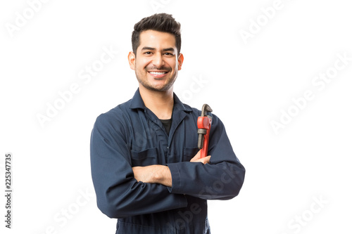 Smiling Male Plumber With Pipe Wrench Standing Arms Crossed