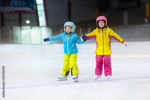Children skating on ice rink. Kids winter sport.