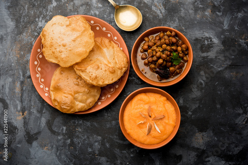 Suji/Sooji Halwa Puri or Shira Poori with black chana masala breakfast, served in a plate and bowl. selective focus