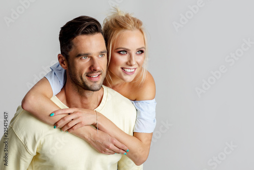 Beautiful young adult couple looking right on empty space, isolated on gray background